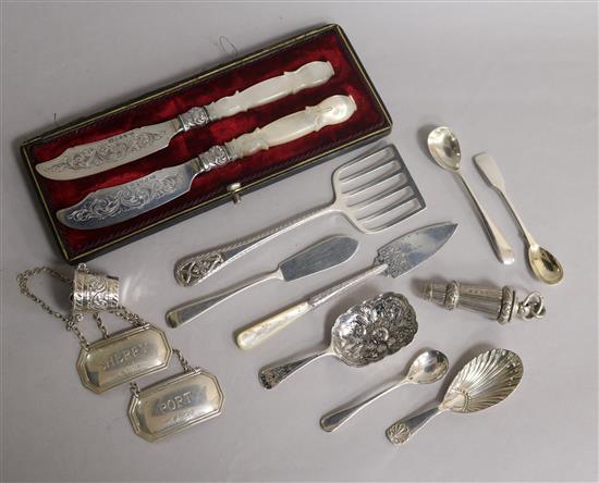 A cased pair of Victorian silver butter knives and twelver other silver items including, wine labels, whistle, caddy spoons etc